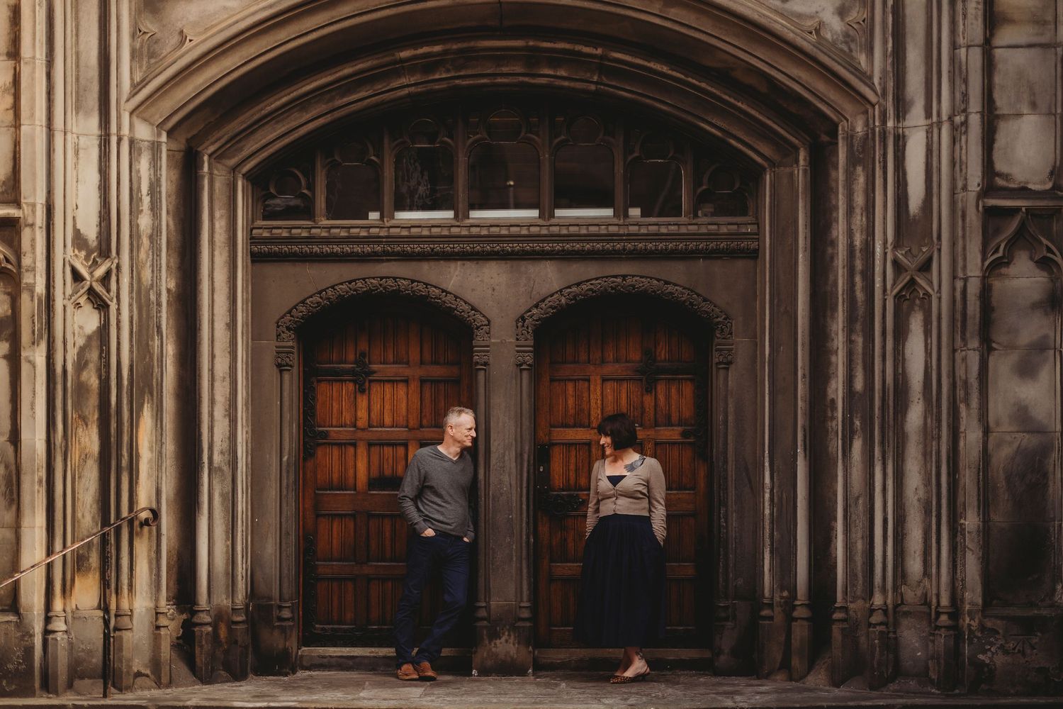 Gothic stone archway entrance to a historic building with ornate architectural details and wooden doors.