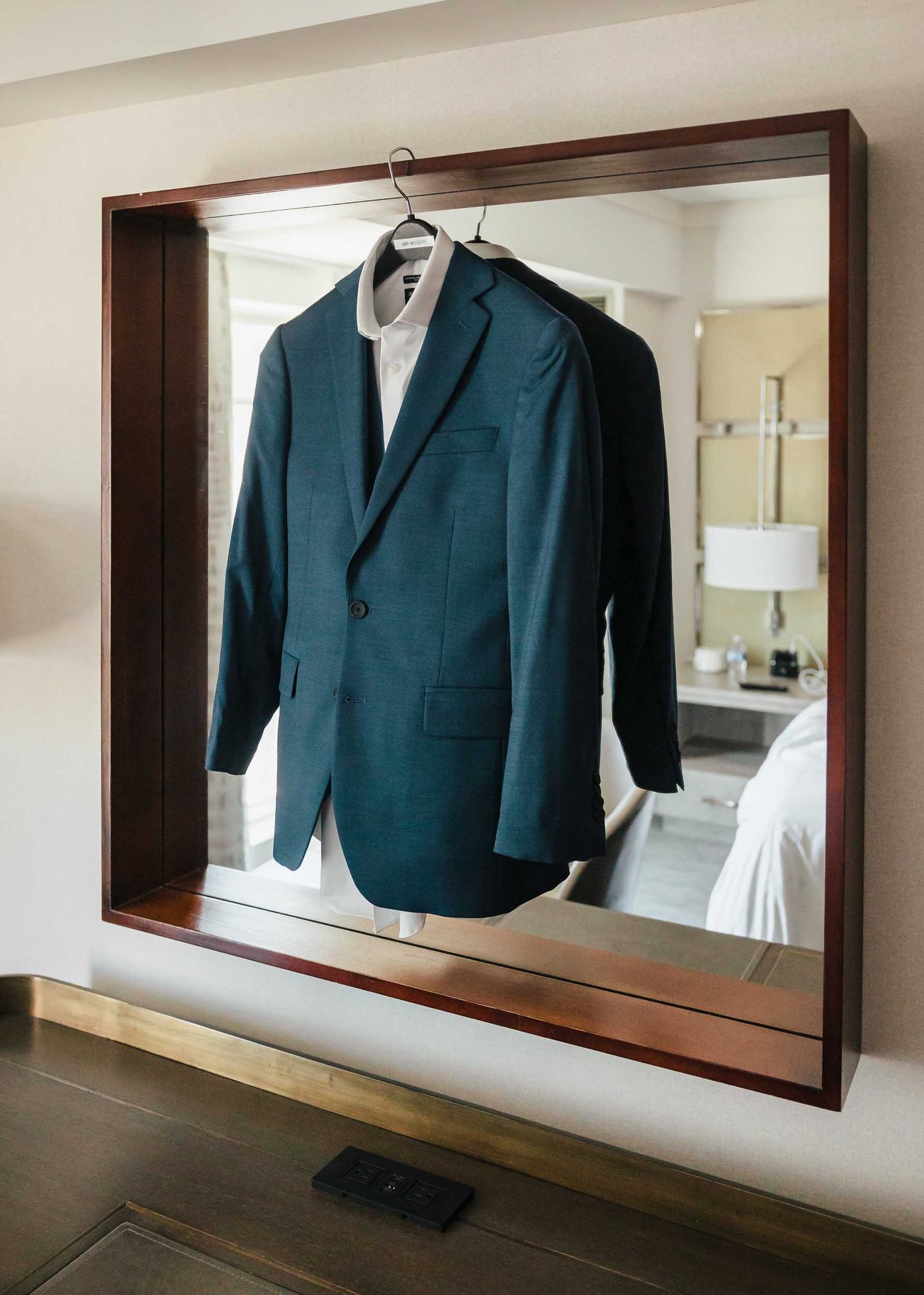 Groom’s navy wedding suit hanging in hotel room during groom preparations for a Boston wedding