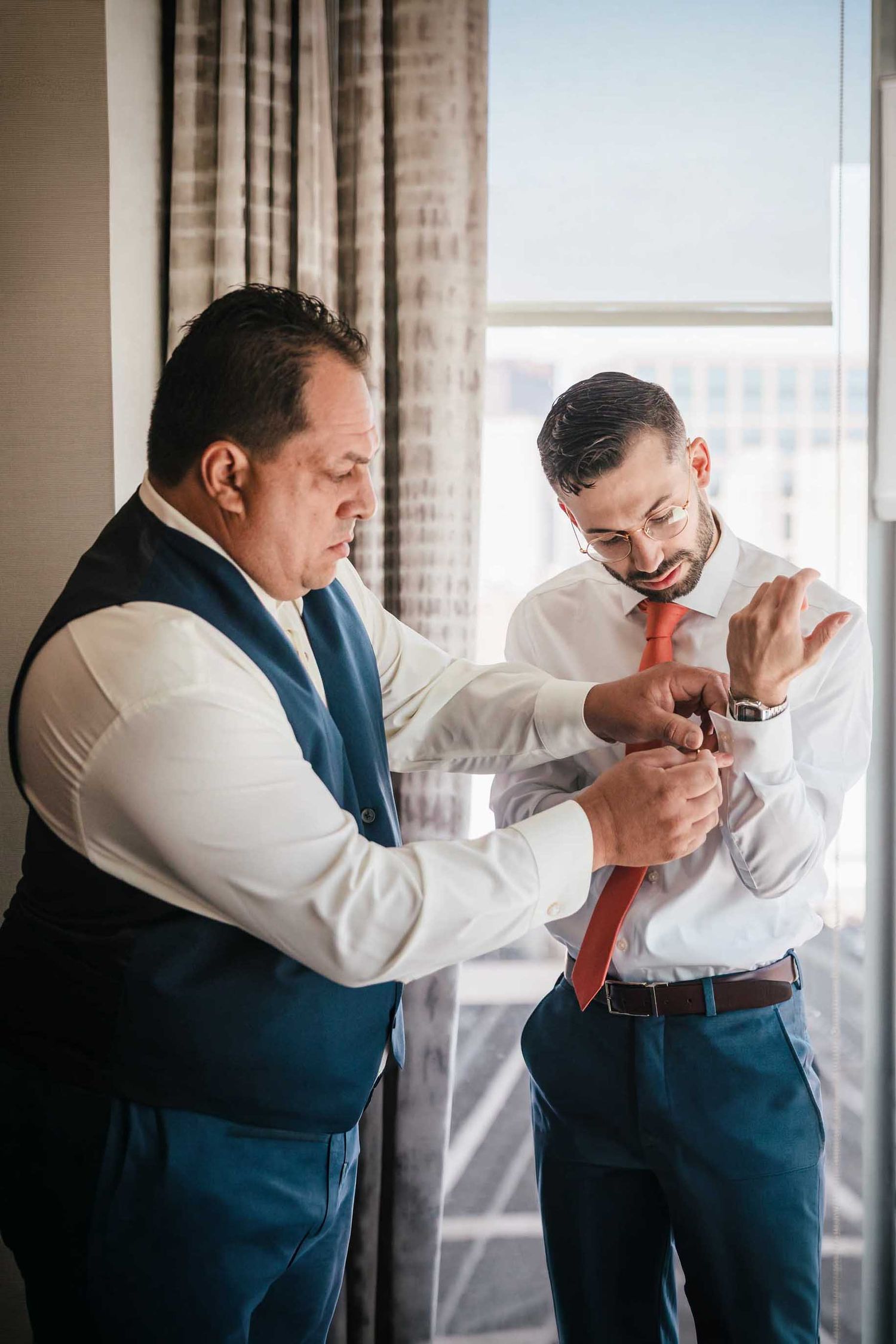 Groom’s father helping him fasten cufflinks while getting ready for a Boston wedding