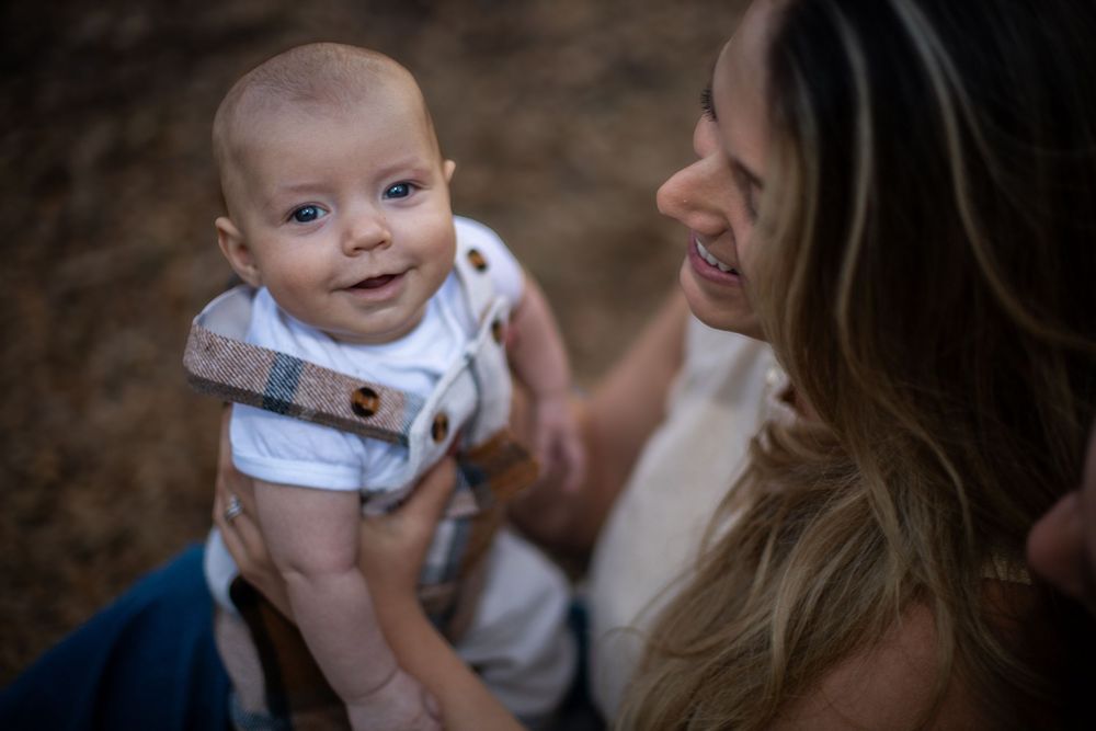 A series of five candid photos showing tender moments between a baby and caregiver in an outdoor setting.