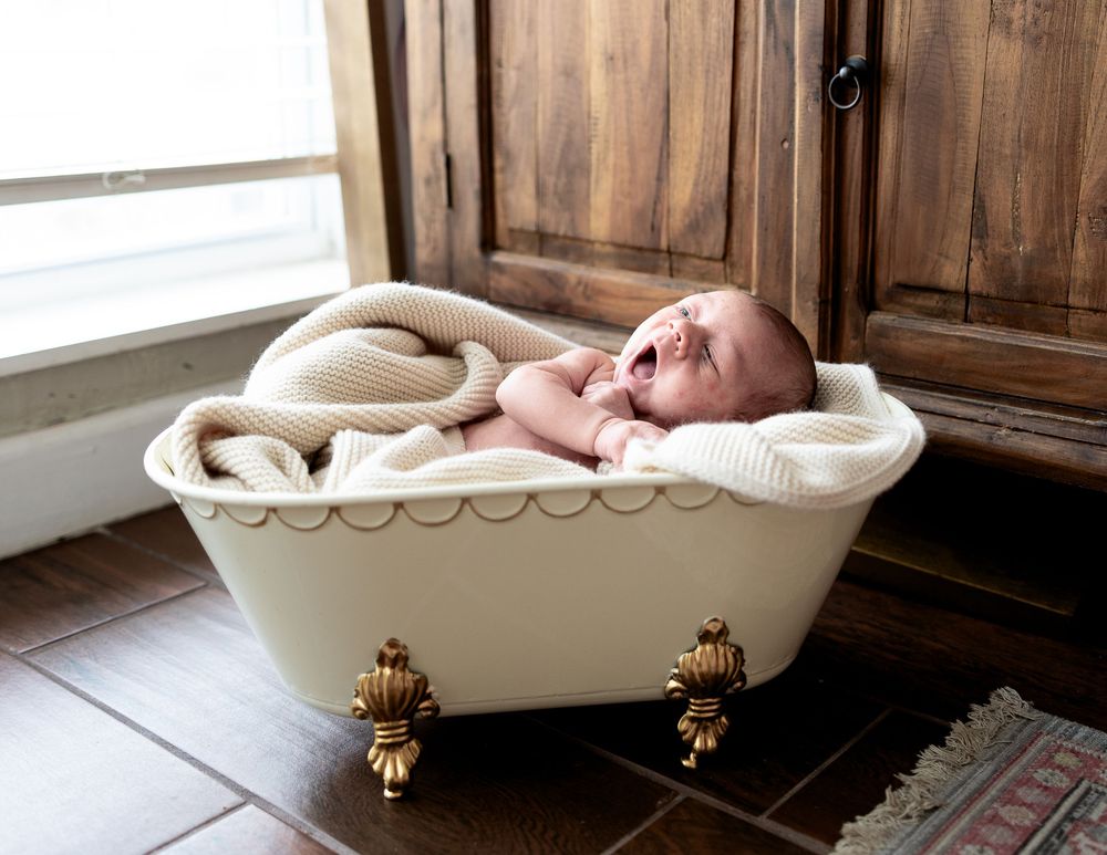 A vintage clawfoot bathtub with brass feet sits against a wooden wall in a rustic bathroom interior.