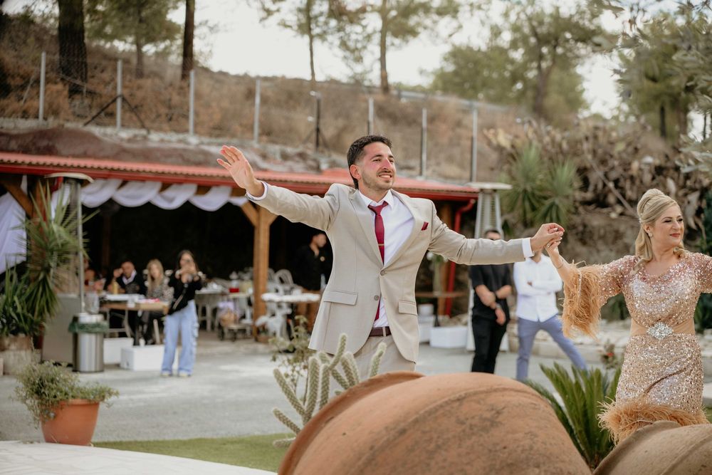 Joyful wedding celebration at outdoor venue with dancing couple in elegant attire on sunny day.