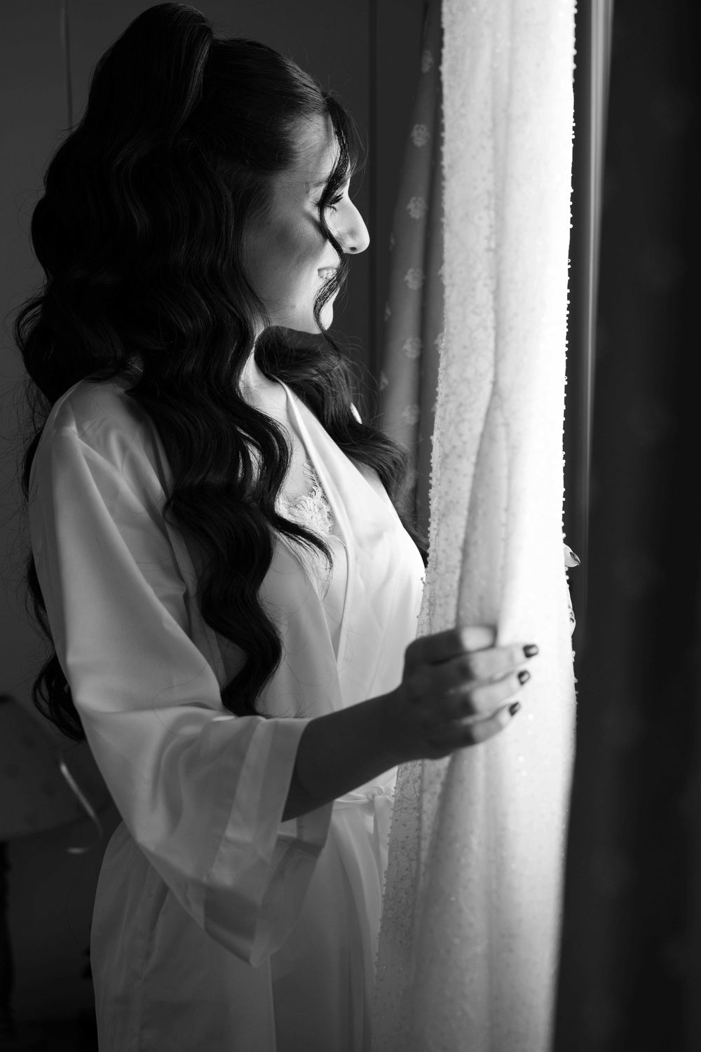 A figure in a white shirt stands near sheer curtains in a moody black and white photo series.
