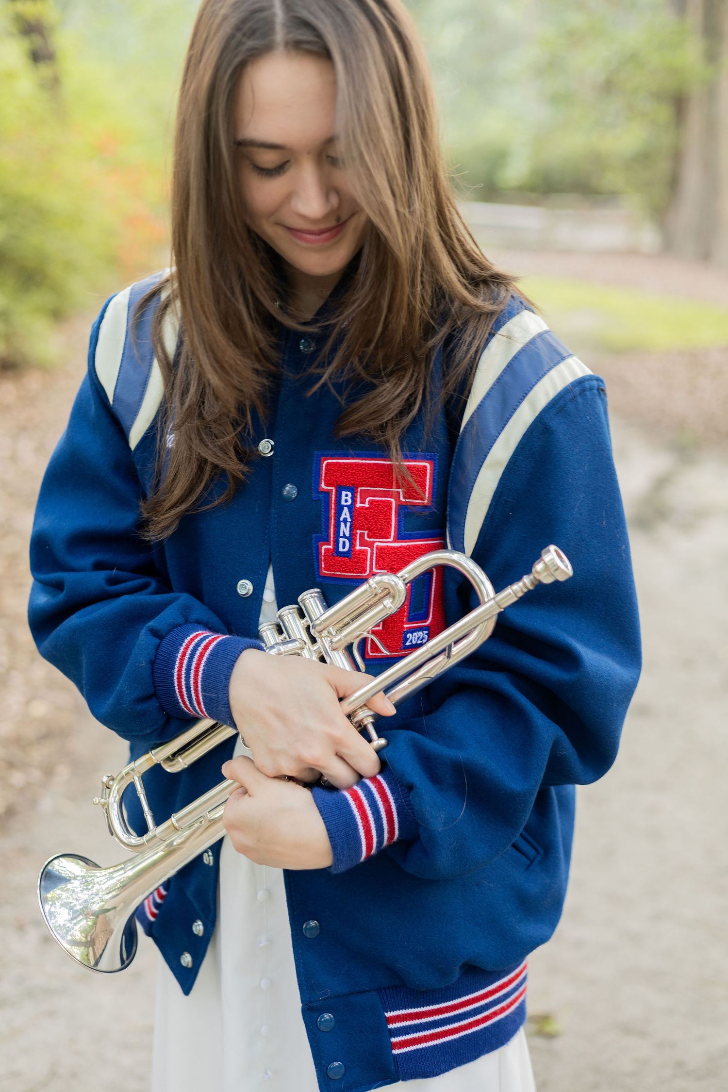 A series of photos showing someone wearing a blue varsity jacket while holding a trumpet in various poses outdoors.