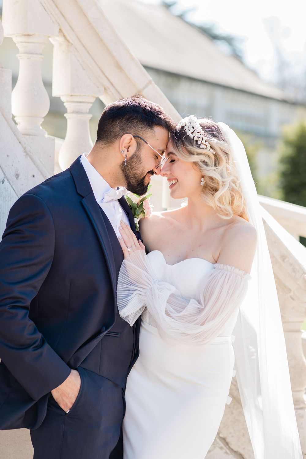 Romantic wedding couple sharing an intimate moment against a white architectural backdrop.