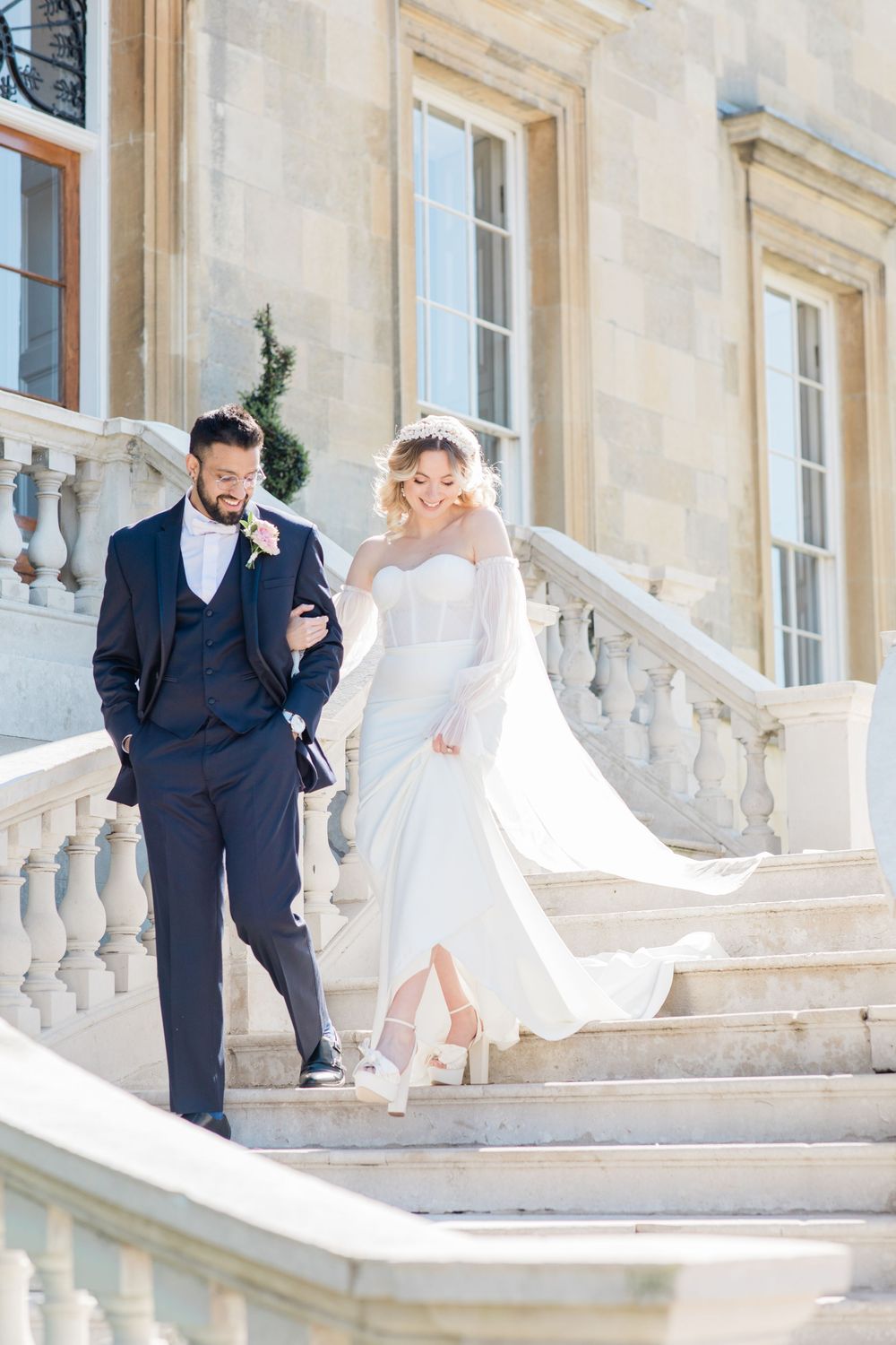 Romantic couple dancing on grand stone steps outside a historic mansion with flowing white dress in motion.