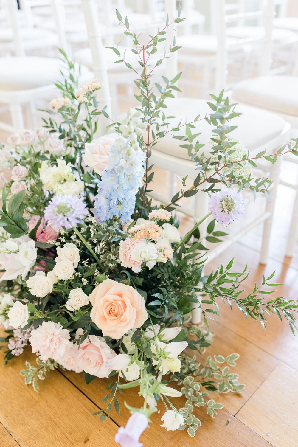Elegant floral centerpieces with peach roses and white blooms arranged on wooden tables.