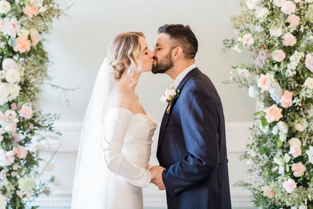 Romantic wedding scene with couple sharing intimate moments among beautiful floral arrangements.