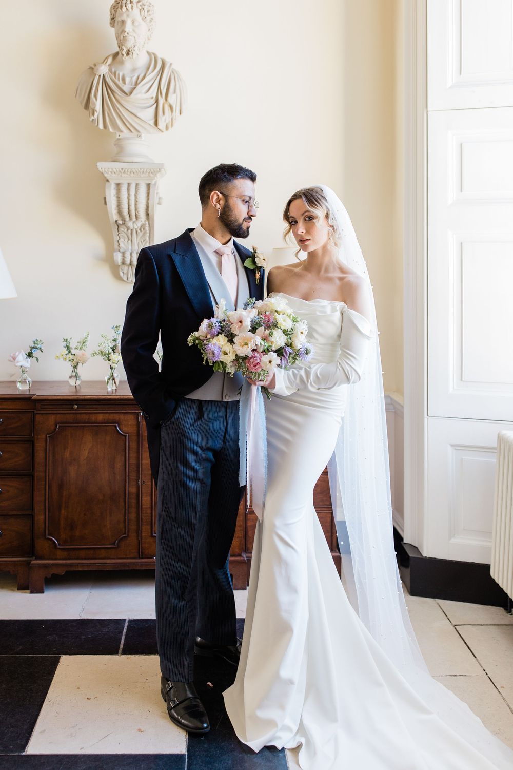 Elegant wedding portraits in a classical room with ornate wall sculptures and antique furniture.