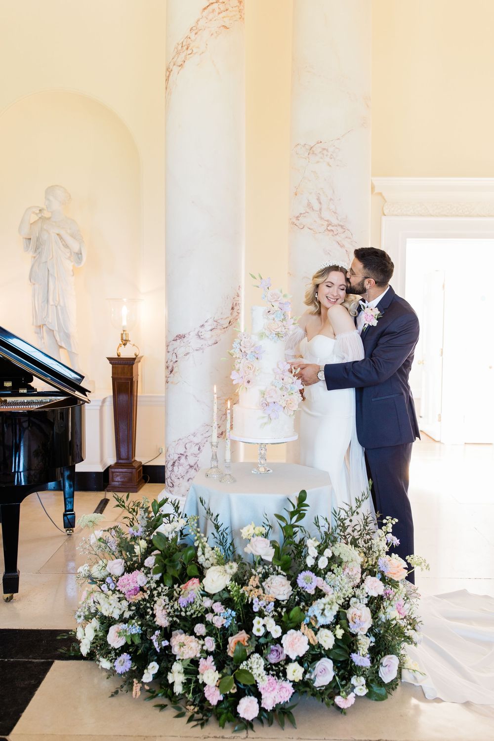 Elegant wedding scene in a light-filled room with white columns and lavish floral arrangements near a grand piano.