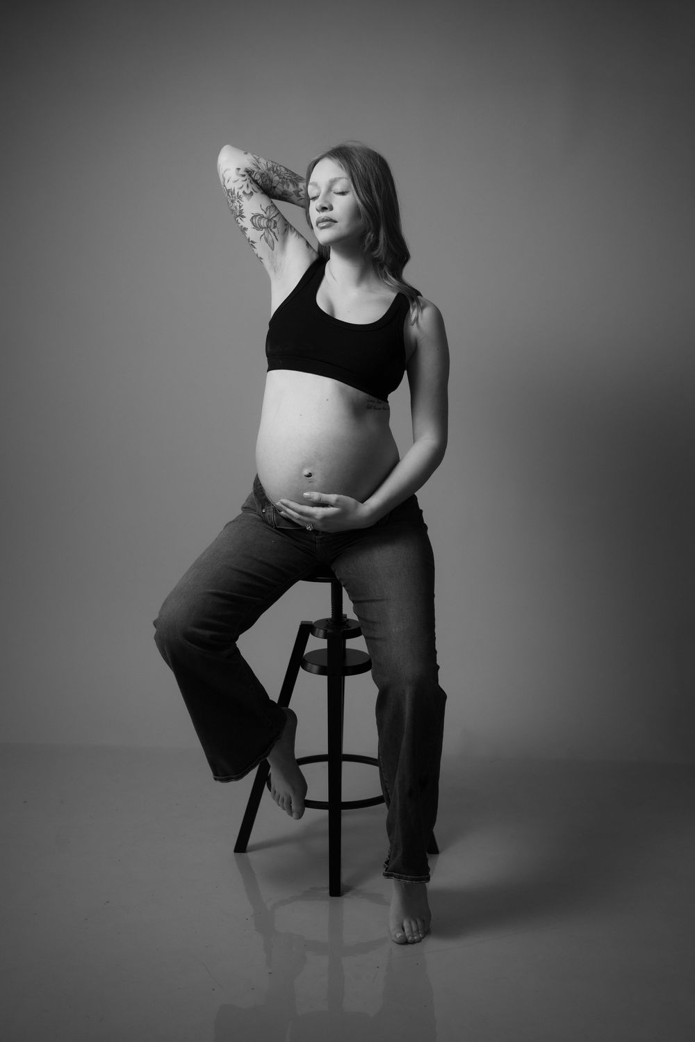 Black and white artistic maternity photo series showing pregnant figure seated on stool in various graceful poses.