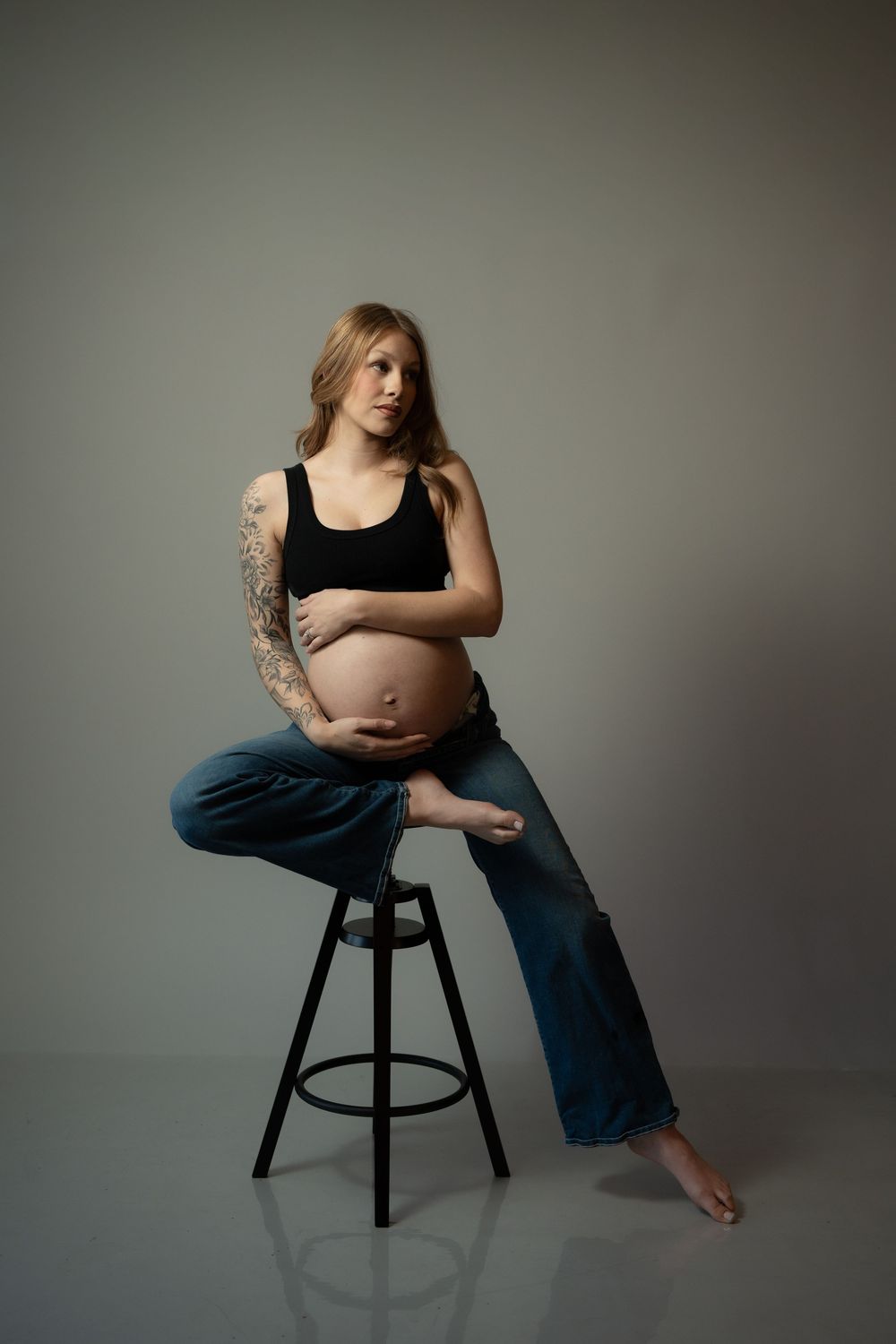 Artistic studio portraits showing figure seated on dark stool against neutral backdrop in various contemplative poses.