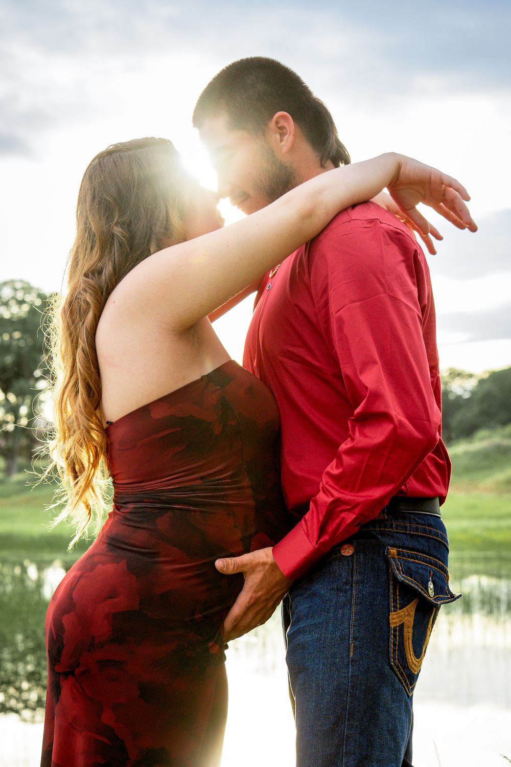 A young couple embracing each other in a romantic outdoor setting with a scenic background.