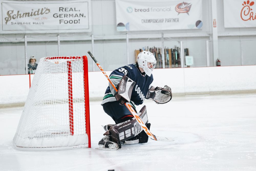 Hockey players practicing on ice rink with red and white goal nets visible.