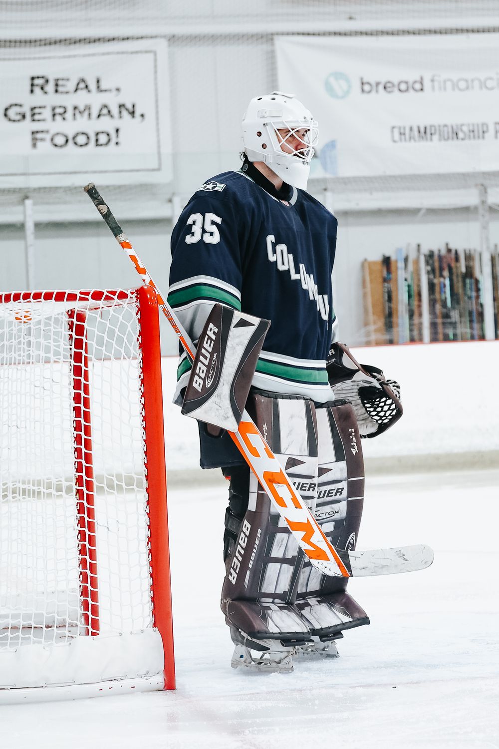 Ice hockey goalie in dark uniform defending net during practice or game.