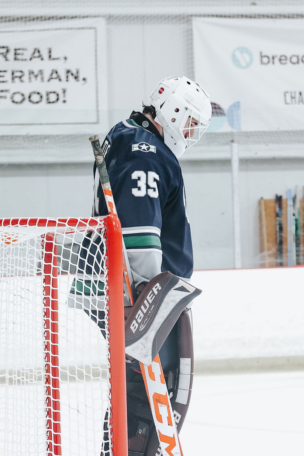 Goalie in navy uniform stands ready at the hockey net during practice.