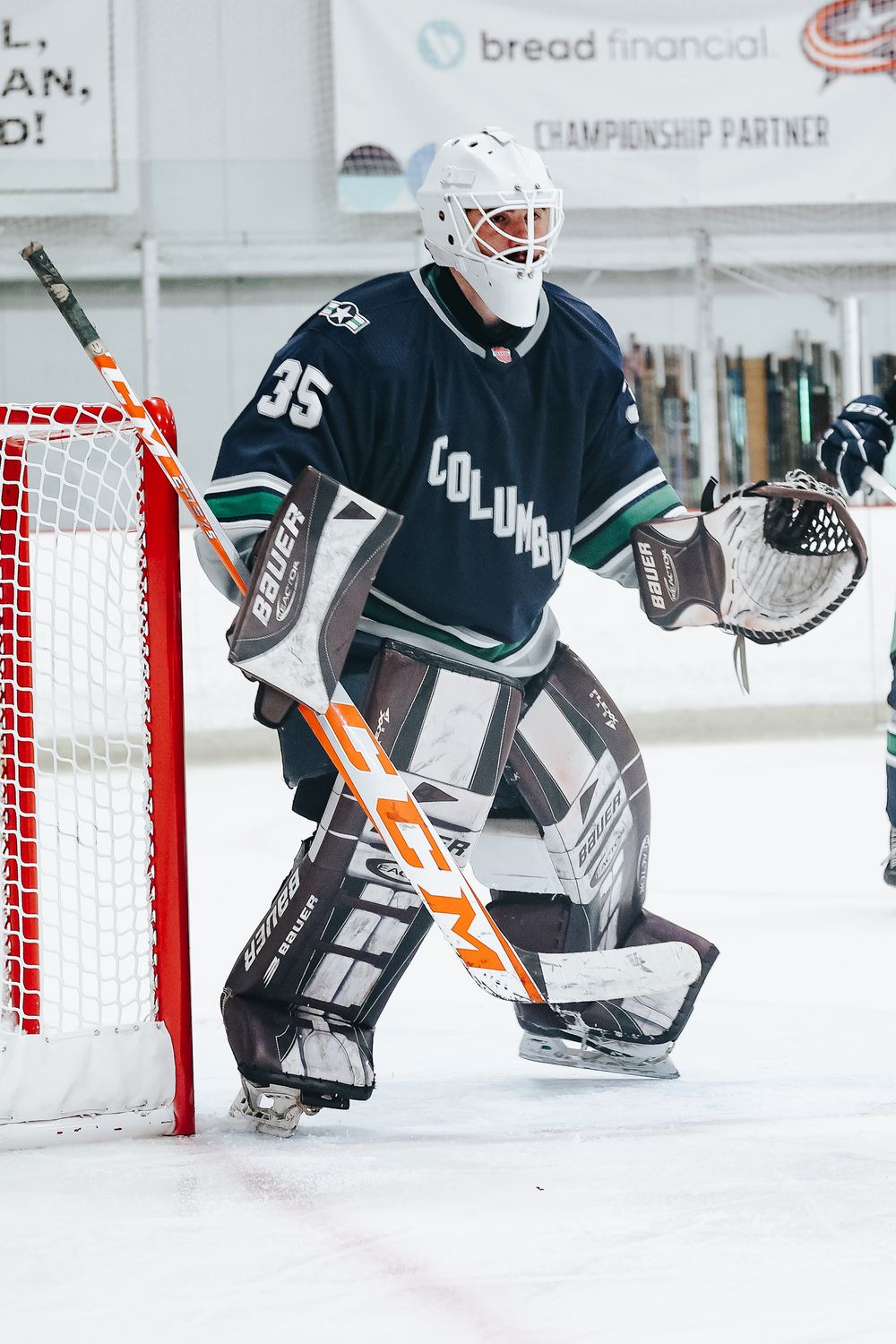 Goalie in protective gear defends net during hockey practice session.