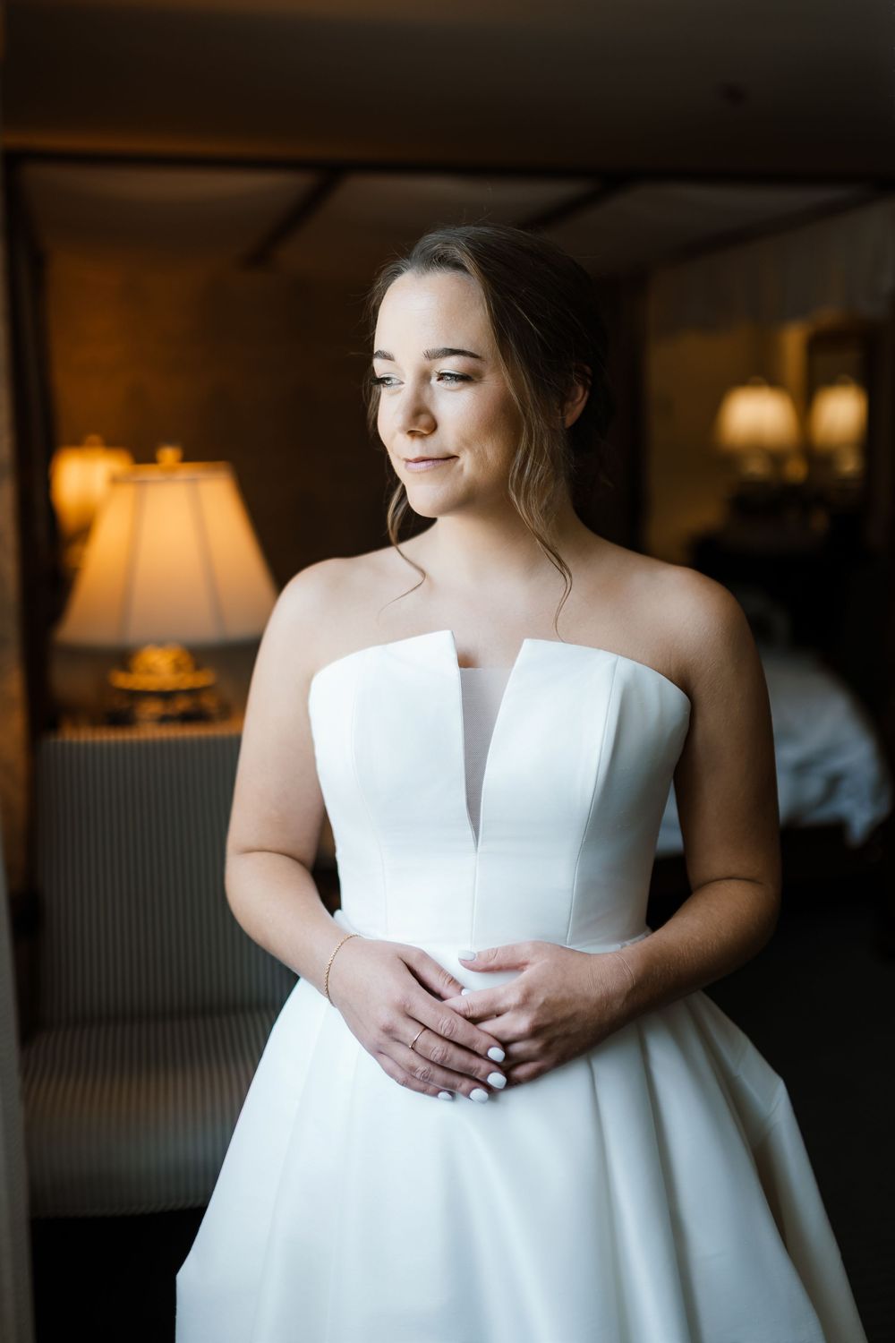 Close-up details of a strapless white wedding gown with structured bodice in natural window light.