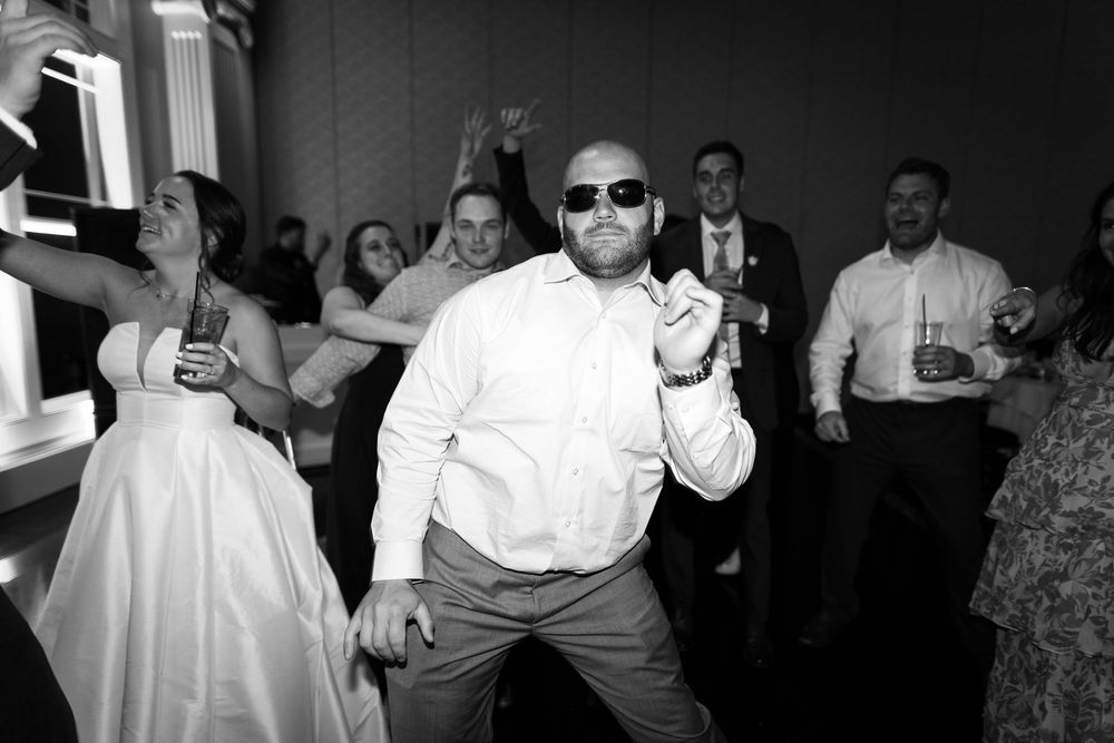 People dancing and celebrating at a wedding reception in black and white photography.