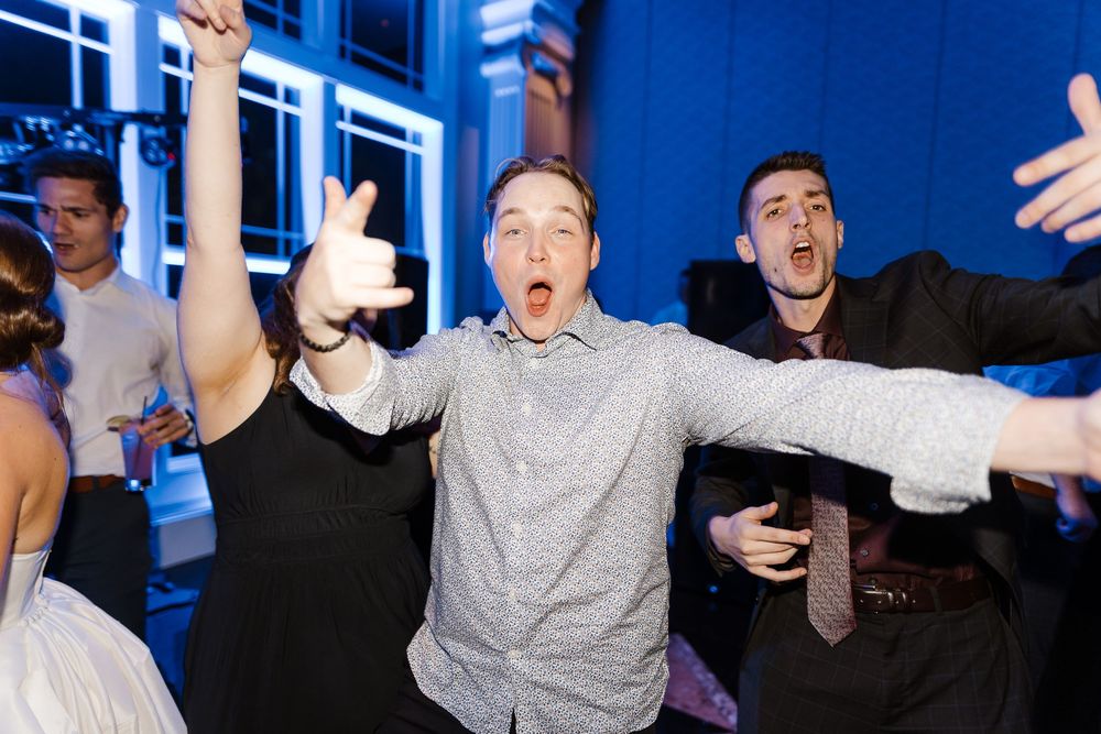A group of performers on stage express dramatic reactions during a theatrical performance with blue lighting.
