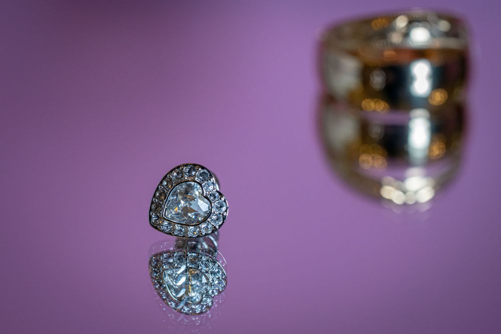 Wedding rings and jewelry displayed on purple background with soft focus.