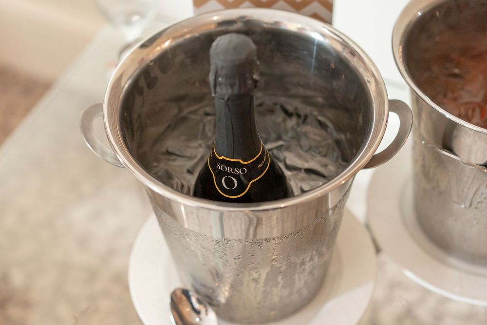 Multiple silver champagne buckets arranged in a row.