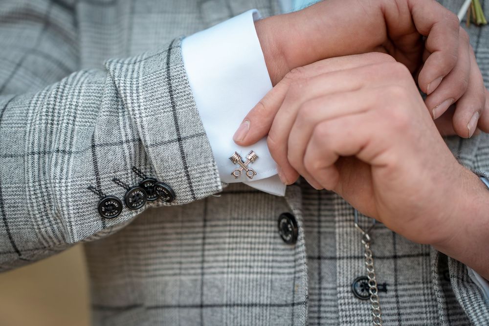 Close-up of hands adjusting a gray plaid suit jacket sleeve and cuff.