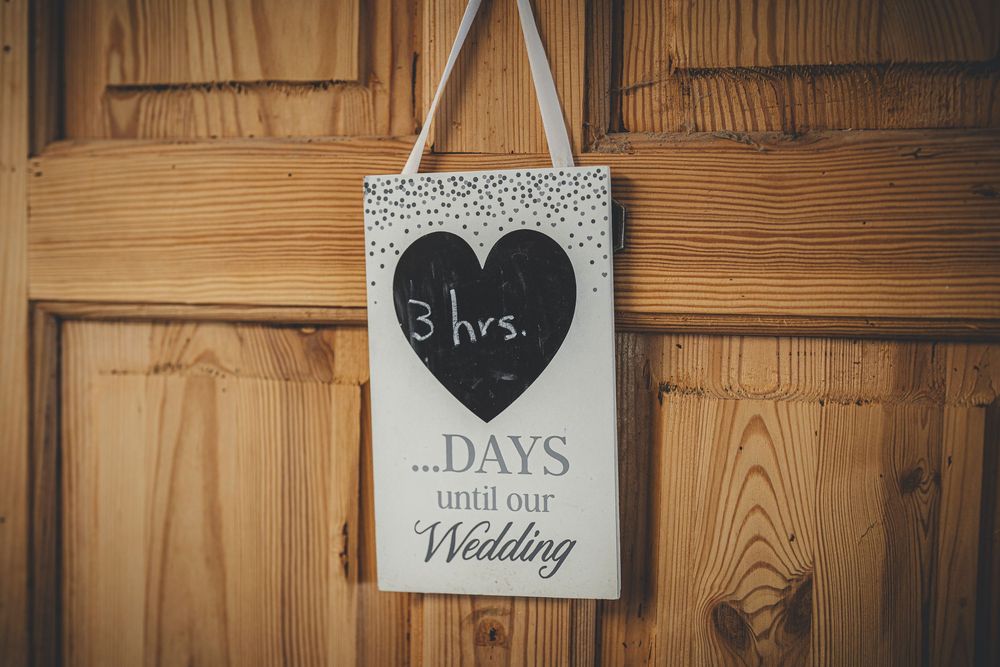 Wooden wall with hanging countdown signs and wedding decor in rustic style.