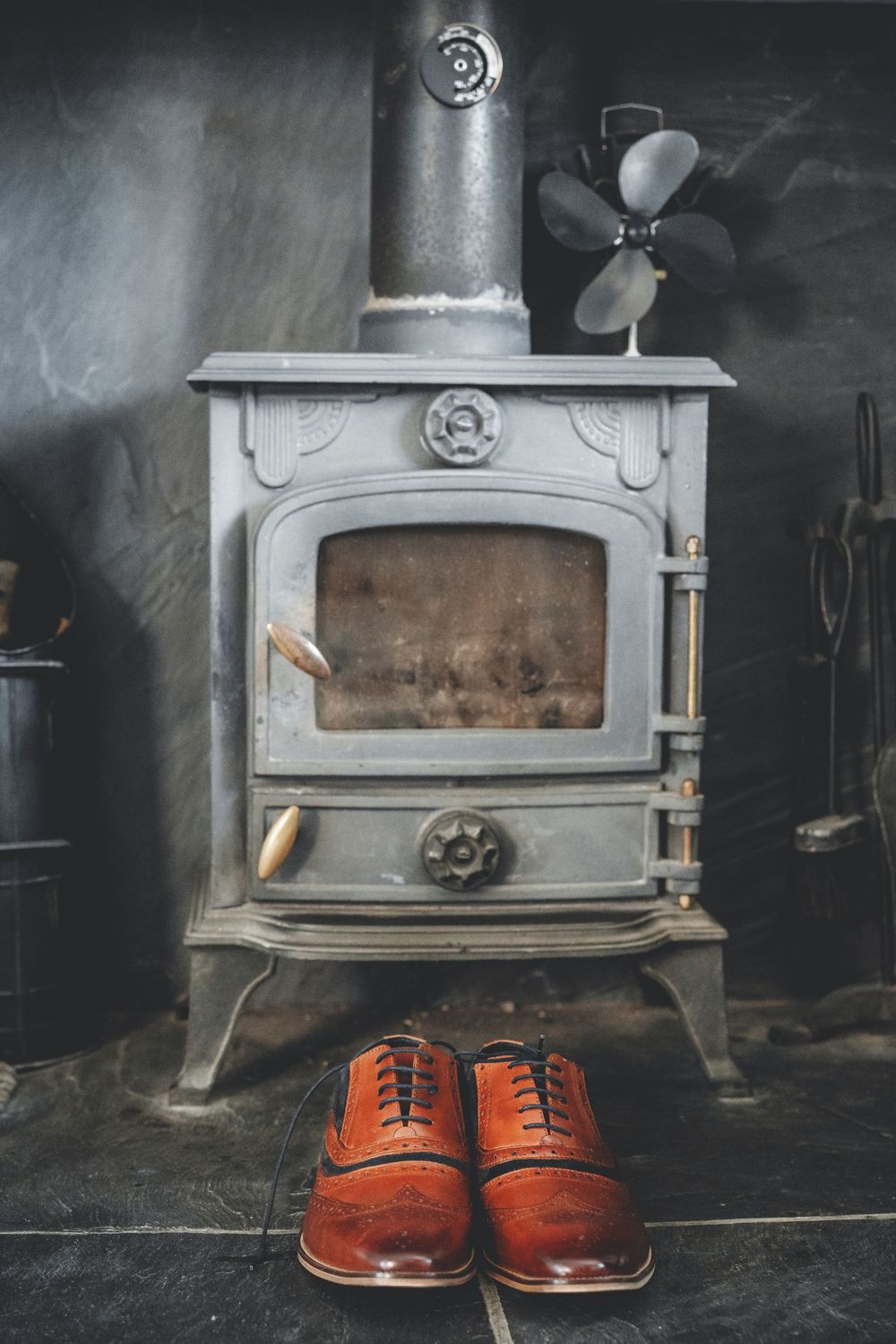 Vintage wood stove with red leather shoes placed in front.