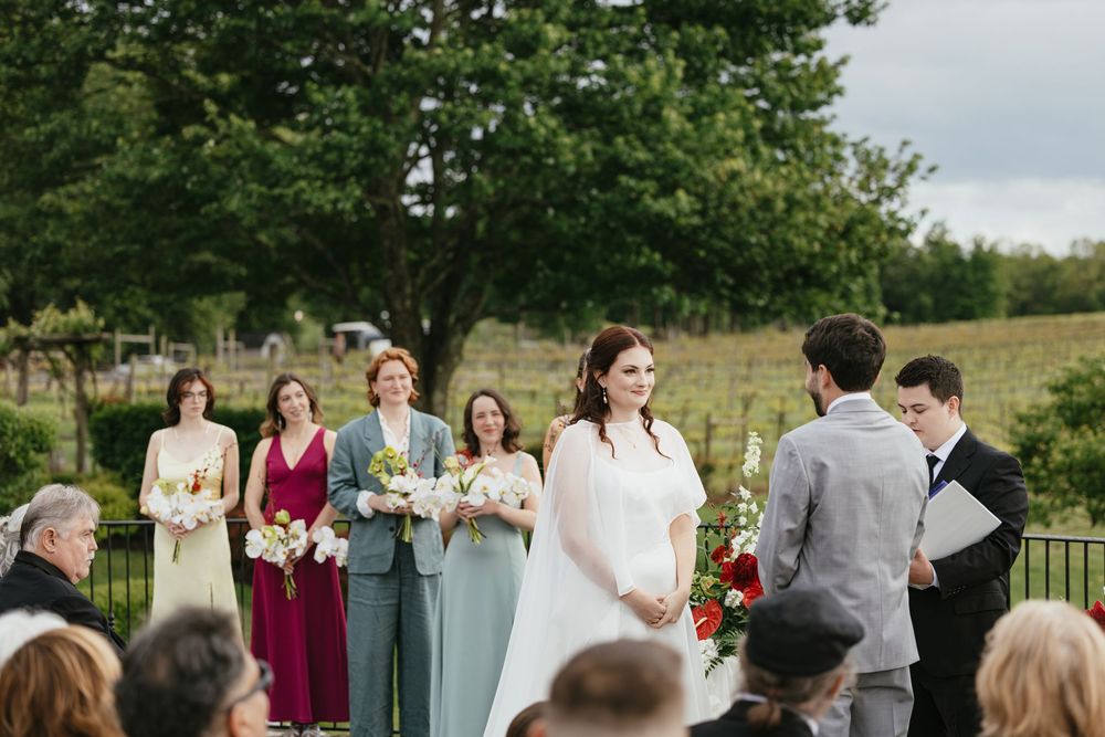 Wedding party and guests gathered outdoors for a summer ceremony with burgundy and blue color scheme.