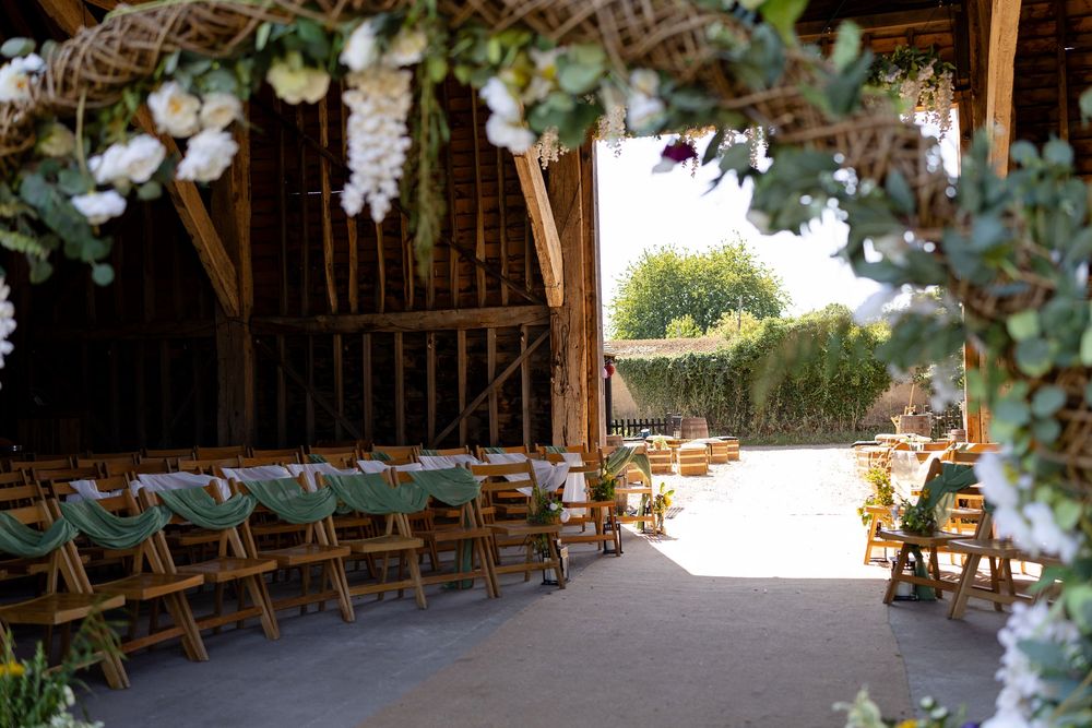 A rustic wedding venue interior with wooden benches and floral decorations lining the aisle.