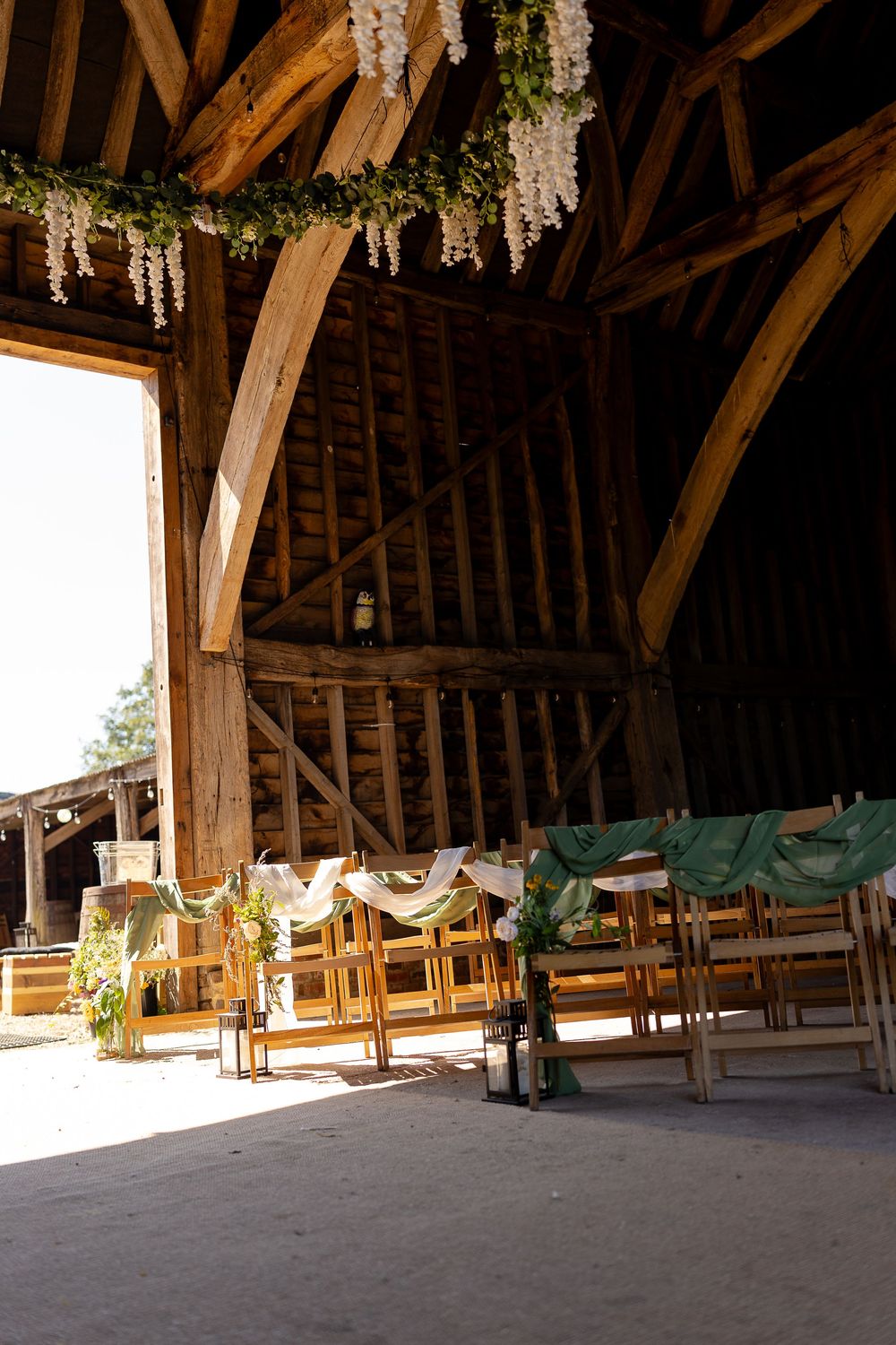 Rustic wooden barn interior with exposed beams and hanging floral decorations creating an elegant event space.