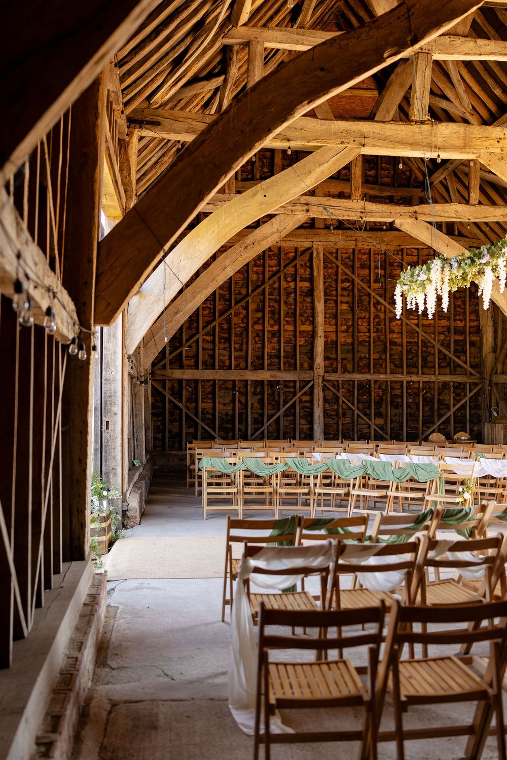 Interior of a rustic barn wedding venue with wooden beams and rows of chairs set up for ceremony.