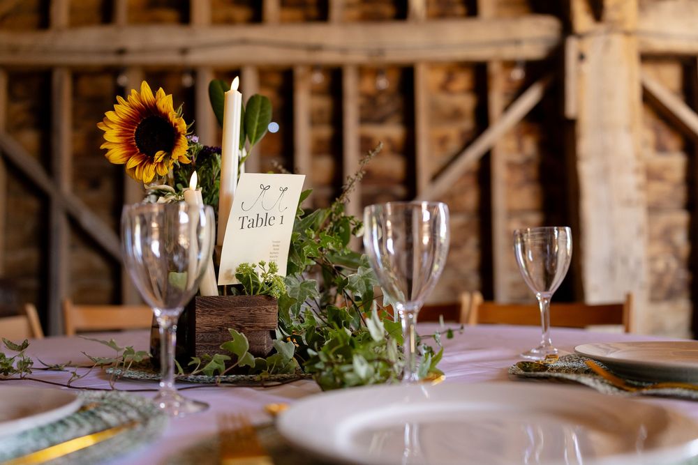 Elegant rustic wedding table setting with sunflower centerpiece and wine glasses.
