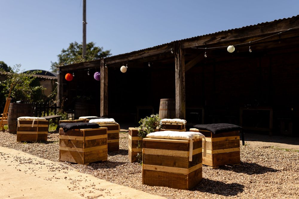 Outdoor seating area with wooden benches arranged in rows on gravel under a covered shelter.