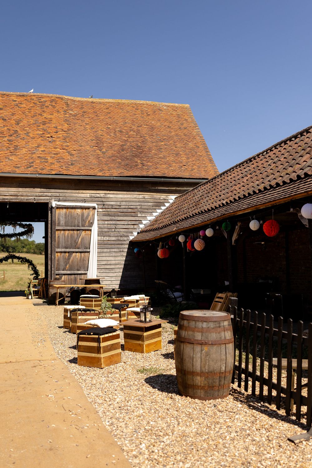Rustic barn exterior with wooden barrels and lanterns decorating the outdoor patio space.