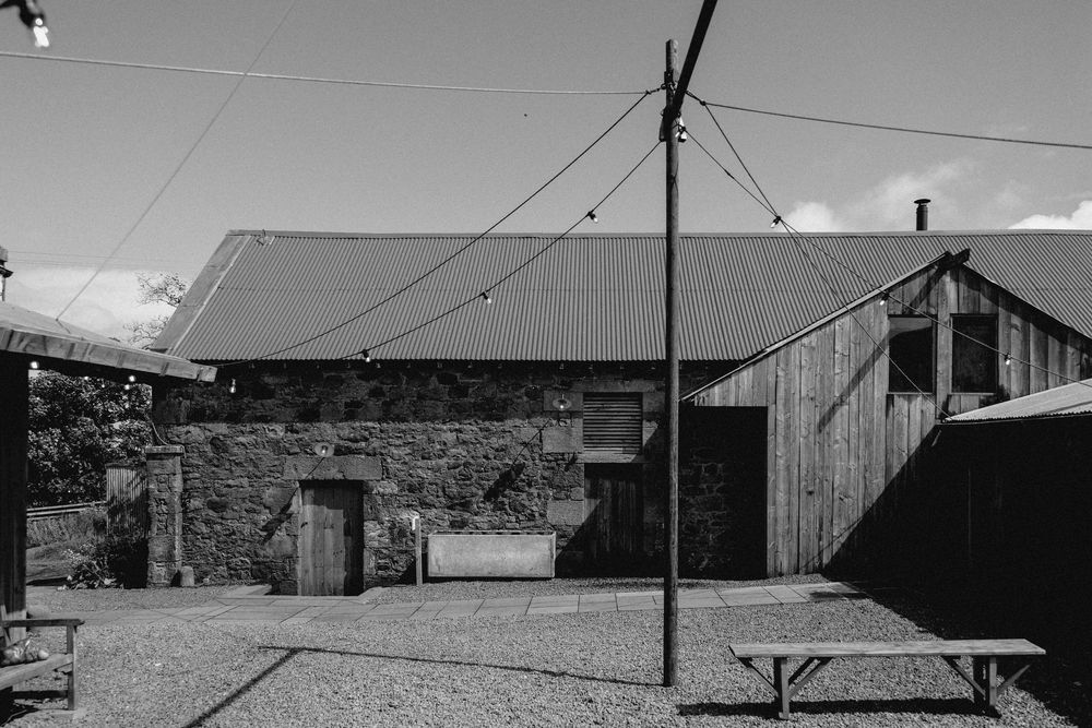 Vintage black and white photograph of a rural farm with multiple barns and outbuildings against a cloudy sky.