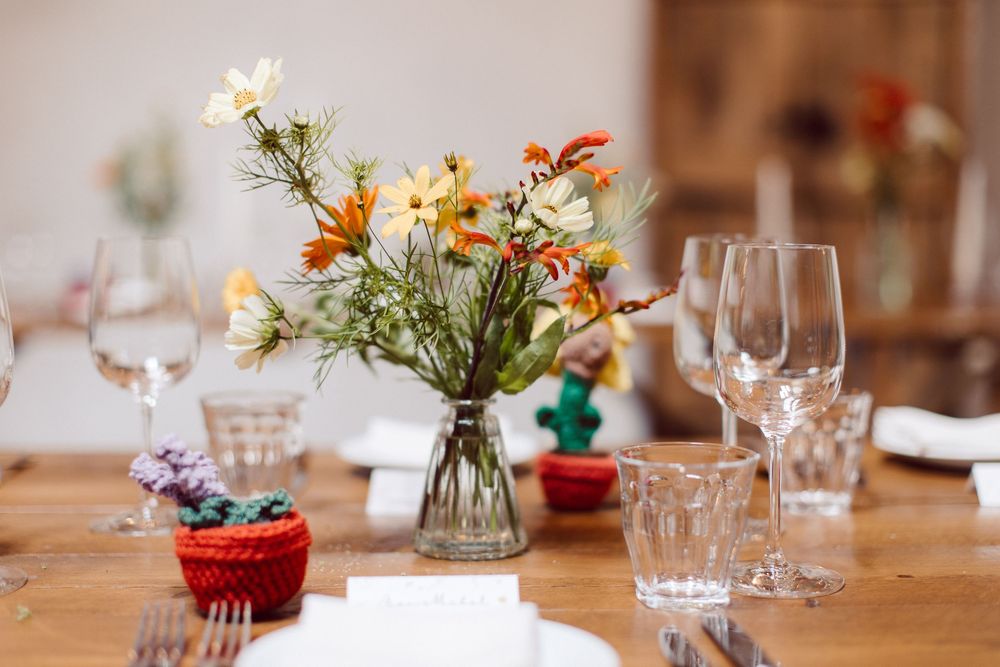 Elegant table setting with fresh flowers and wine glasses in warm natural lighting at a rustic restaurant.