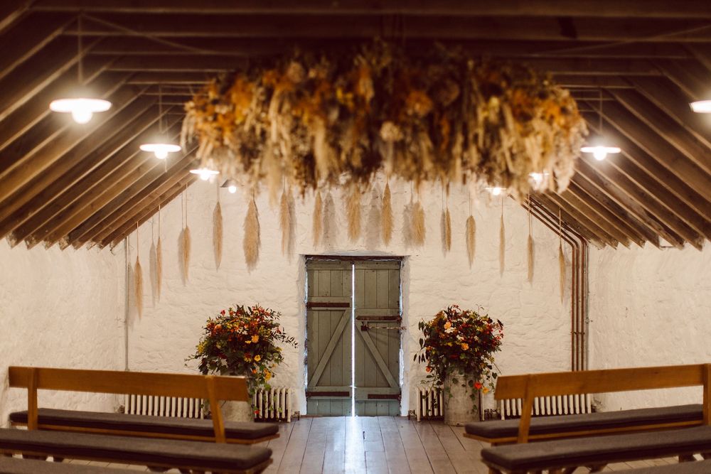 Rustic barn interior decorated with dried flowers and wooden beams for a wedding reception venue.