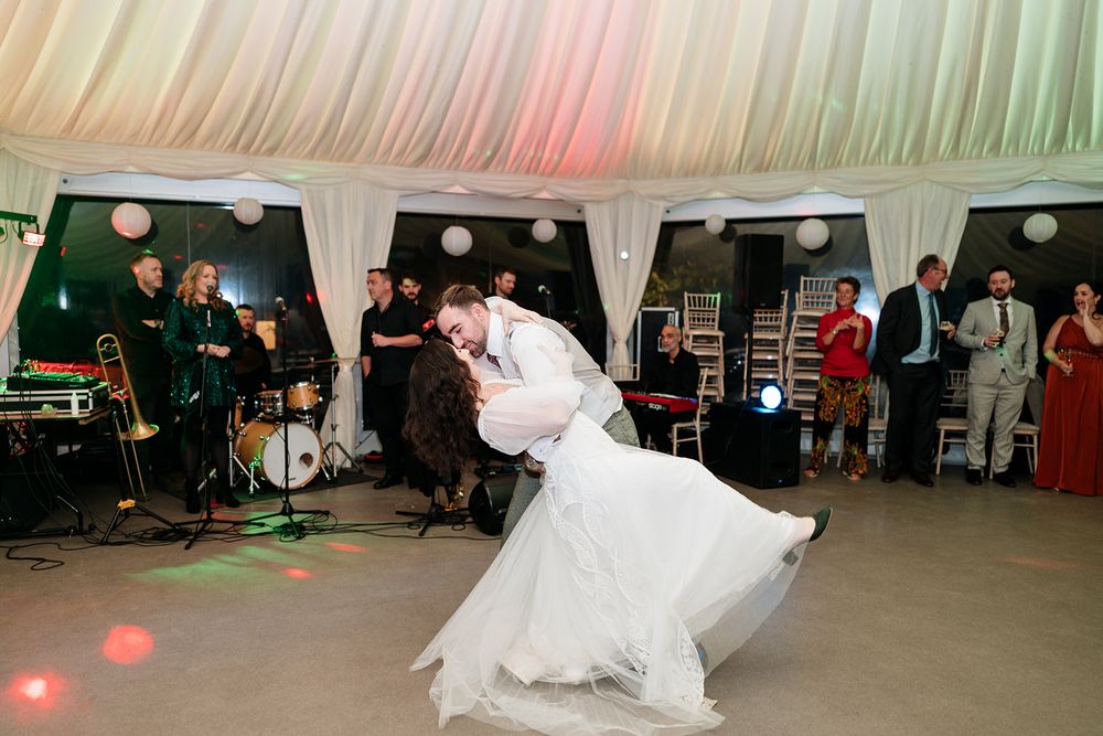Wedding reception dance floor filled with guests enjoying a celebration under soft lighting and paper lanterns.