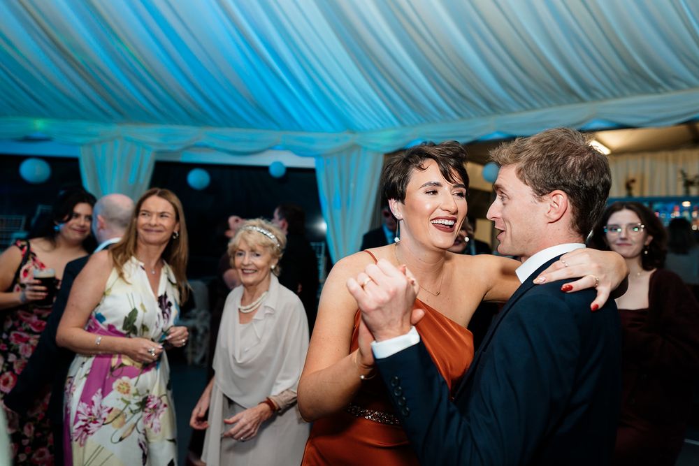 People dancing and celebrating together at a party with blue lighting and festive atmosphere.