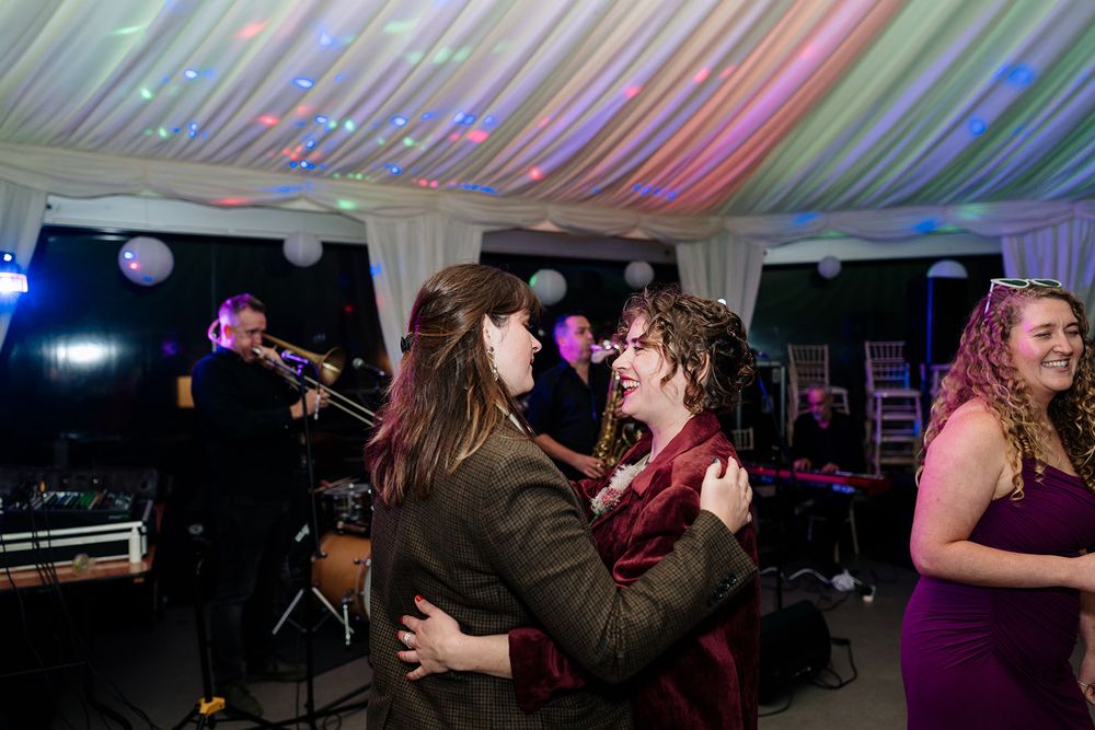People dancing and socializing at a lively party under a tent with colorful lighting effects.