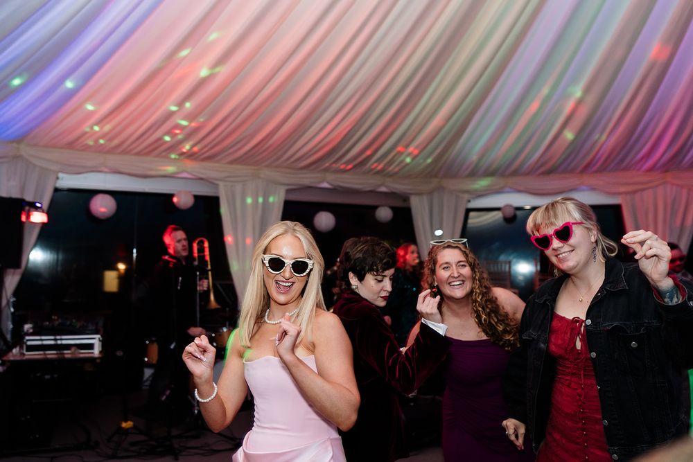 Guests enjoying themselves on a dance floor beneath a draped tent ceiling with atmospheric lighting.