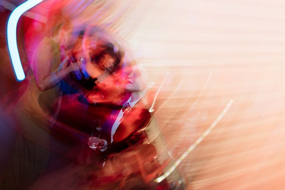 Abstract long exposure photograph with blurred red and pink motion streaks against a dark background creating a dynamic pattern.