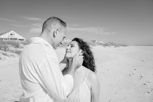 Black and white portrait captures tender moments during a beach wedding shoot.