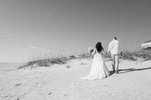 Black and white wedding photography captures intimate moments on a sandy beach.