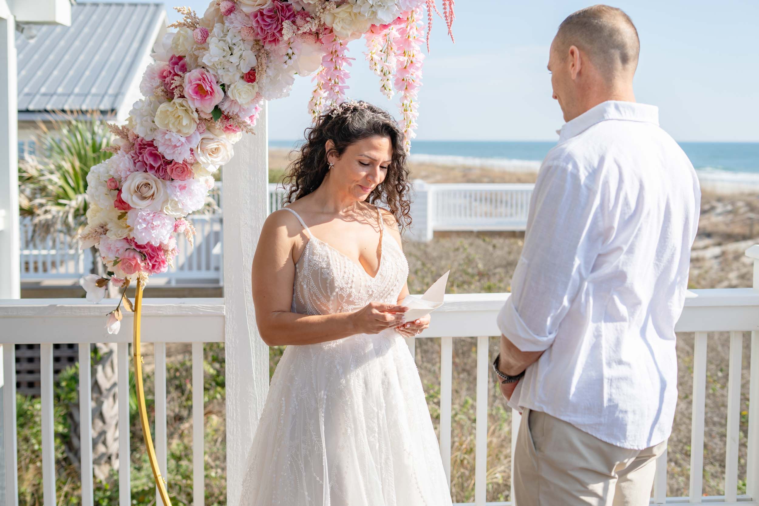 Beachside wedding ceremony with ocean view and floral decorations.