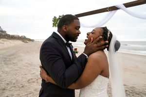 Joyful celebration between newlyweds on a beach with waves in the background.