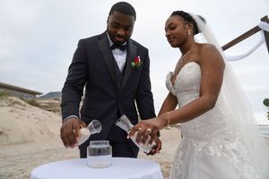 Couple participating in a sand ceremony ritual at their beach wedding.