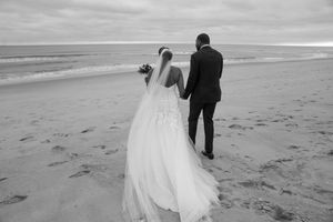 Black and white photo of newlyweds enjoying moments on a windswept beach.